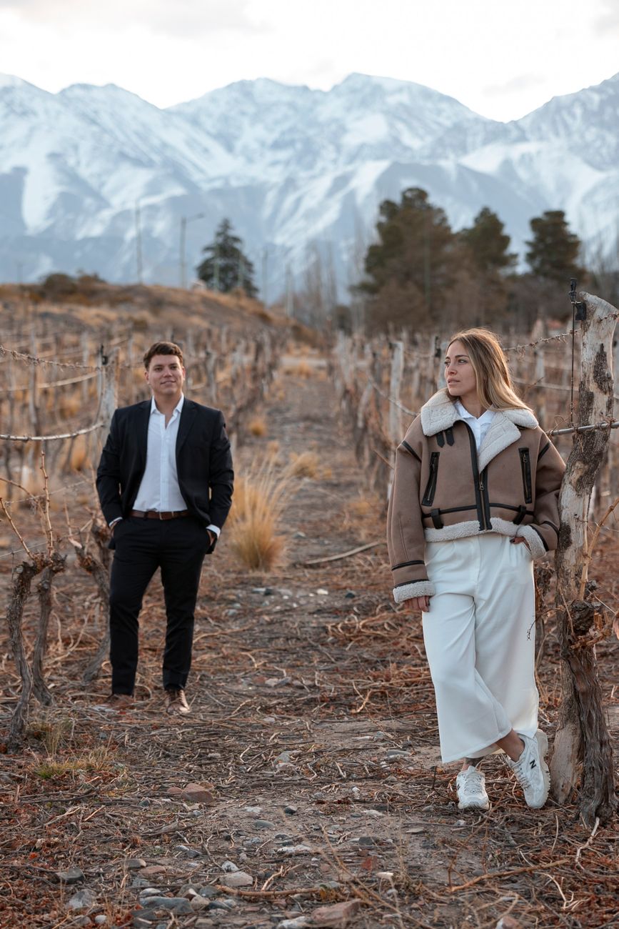 Hileras de vides y copas de vino con la cordillera al fondo